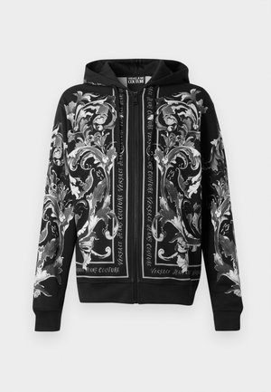 Black zip-up hoodie featuring intricate silver floral patterns and text accents, with a soft texture and long sleeves.