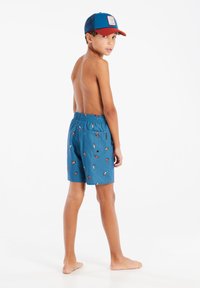 Boxer da bagno blu con una stampa vivace di bevande, vita elasticizzata e tasca posteriore, abbinati a un cappellino blu e rosso.