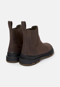 Bottines en cuir marron avec des panneaux élastiques sur les côtés et des languettes de tirage. Présentent une semelle noire épaisse avec une semelle texturée pour une meilleure adhérence.