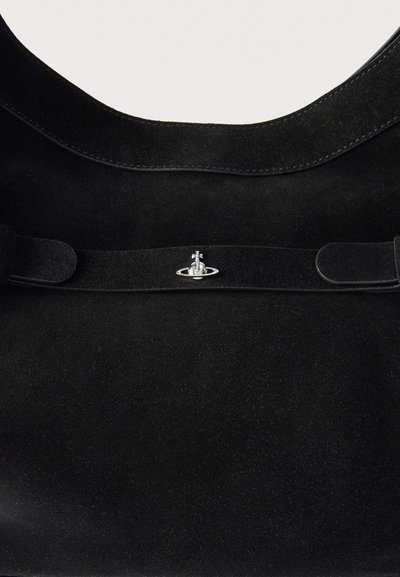 Μαύρη τσάντα tote από σουέντ με ασημένιο κούμπωμα σε σχήμα σφαίρας, τοποθετημένο στο κέντρο του πάνω λουριού, σε απλό φόντο.