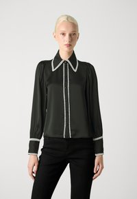 Bluză verde închis din satin, cu un guler mare alb și accente cu nasturi albi. Mâneci lungi cu umeri gathered și detalii la manșete.
