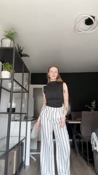 Melna bezpiedurkņu blūze un baltas svītrainas plašas bikses. Gluda auduma, pieguloša forma augšpusē, biksēm krokas. Minimalistisks dizains, nav papildu rakstu.