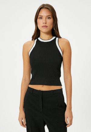 Top corto negro con acanaladuras y cuello alto, con acentos blancos en el cuello y las sisas, hecho de una tela elástica.