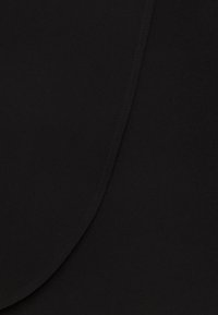 Svart tyg med en slät textur, med en böjd söm längs kanten och subtila stickdetaljer.