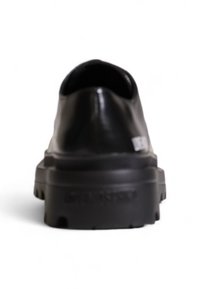 Scarpa in pelle nera con punta arrotondata e suola spessa e testurizzata. Presenta una superficie superiore liscia e un design minimalista.