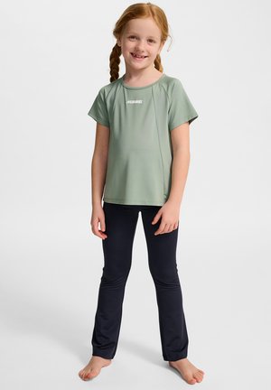 Ljusgrön, kortärmad sporttröja med vitt logo, kombinerad med mörkblå leggings; båda tillverkade av slät, stretchig tyg.