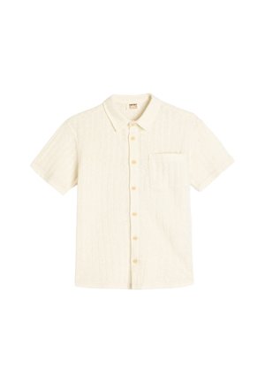 Chemise blanche à manches courtes avec un motif texturé, devant boutonné, col etune poche poitrine unique. Les boutons sont de couleur beige clair.