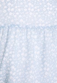 Tessuto blu chiaro con un motivo floreale bianco. Presenta una texture arricciata lungo l'orlo, creando un aspetto morbido e fluido.