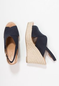 Marina klacksandaler med korsremmar, tygöverdel och en flätad juteplattformssula med dragkedjestängning bak.