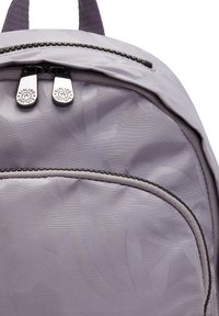 Mochila morada con superficie texturizada, doble cremallera y un bolsillo frontal. Presenta sutiles patrones de hojas y correas ajustables.