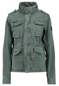 Olijfgroene militaire stijl jas van gestructureerde stof. Heeft een hoge kraag, dubbele borstzakken en opvallende stikdetails.