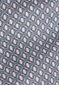 Tissu à motifs en alternance de gris clair et de bleu, présentant un design géométrique avec des ovales interconnectés et des formes rectangulaires.