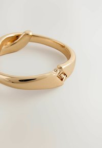 Gold-tone metal bangle bracelet with a smooth, polished finish. Features a secure clasp and a rounded, streamlined design.