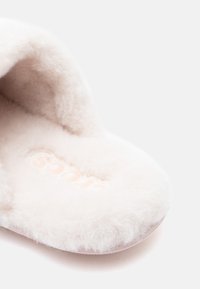 Pehmead, plüüšist roosad sussid, millel on ümar kuju, tekstuuriga karvane pind ja lame tallaosa. Siseosa peal on heledatooniline logo fooliumtrükiga.