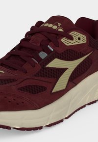 Chaussure de sport bordeaux et beige avec tige en mesh et daim, fermeture à lacets et semelle épaisse et rembourrée visible de profil.
