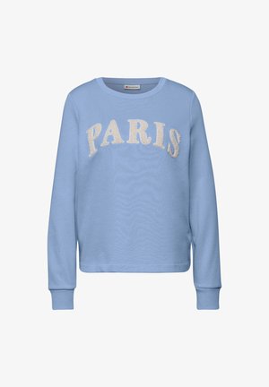 Vaaleansiniset collegepaita pitkillä hihoilla, jossa rinnan kohdalla on ”PARIS”-teksti kermaisenvärisellä, teksturoidulla kirjasimella. Resorireunukset hihoissa ja helmassa.