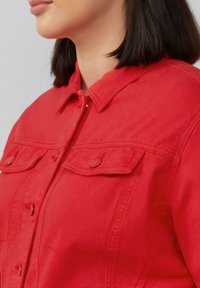 Rote Jeansjacke mit kragenförmigem Hals, knöpfbarem Frontverschluss und zwei Brusttaschen mit Klappen. Glatte Textur und taillierte Passform.