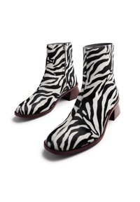 Botines con estampado de cebra, con una superficie suave y texturizada, que presentan un bajo tacón cuadrado y un cierre lateral para facilitar su uso.