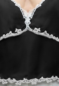 Μαύρο σατινέ τοπ εσωρούχου με περίπλοκη λευκή δαντέλα κατά μήκος του ντεκολτέ, κάτω από το στήθος και το τελείωμα.