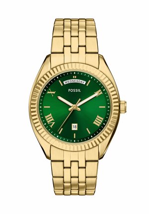 Guldtonad metallklocka med en grön urtavla, romerska siffermarkörer och datumvisning. Har ett länkarmband och en texturerad bezel.