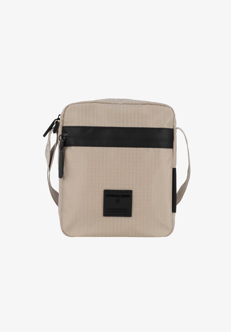 Beige schoudertas van een uitgebalanceerde stof, met een zwart leren accentband, een ritssluiting en een gestikte logopatch aan de voorkant.