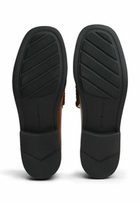 Brązowe skórzane buty z teksturowaną cholewką i czarną gumową podeszwą, z rowkowanym wzorem zapewniającym przyczepność.
