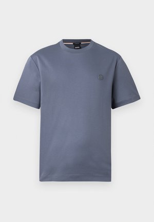 T-shirt bleu-gris uni à manches courtes, col rond et petit logo circulaire sur le côté gauche de la poitrine.