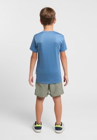 Short-sleeve, blue athletic shirt made of lightweight fabric, paired with green shorts. Features a round neck and simple design.