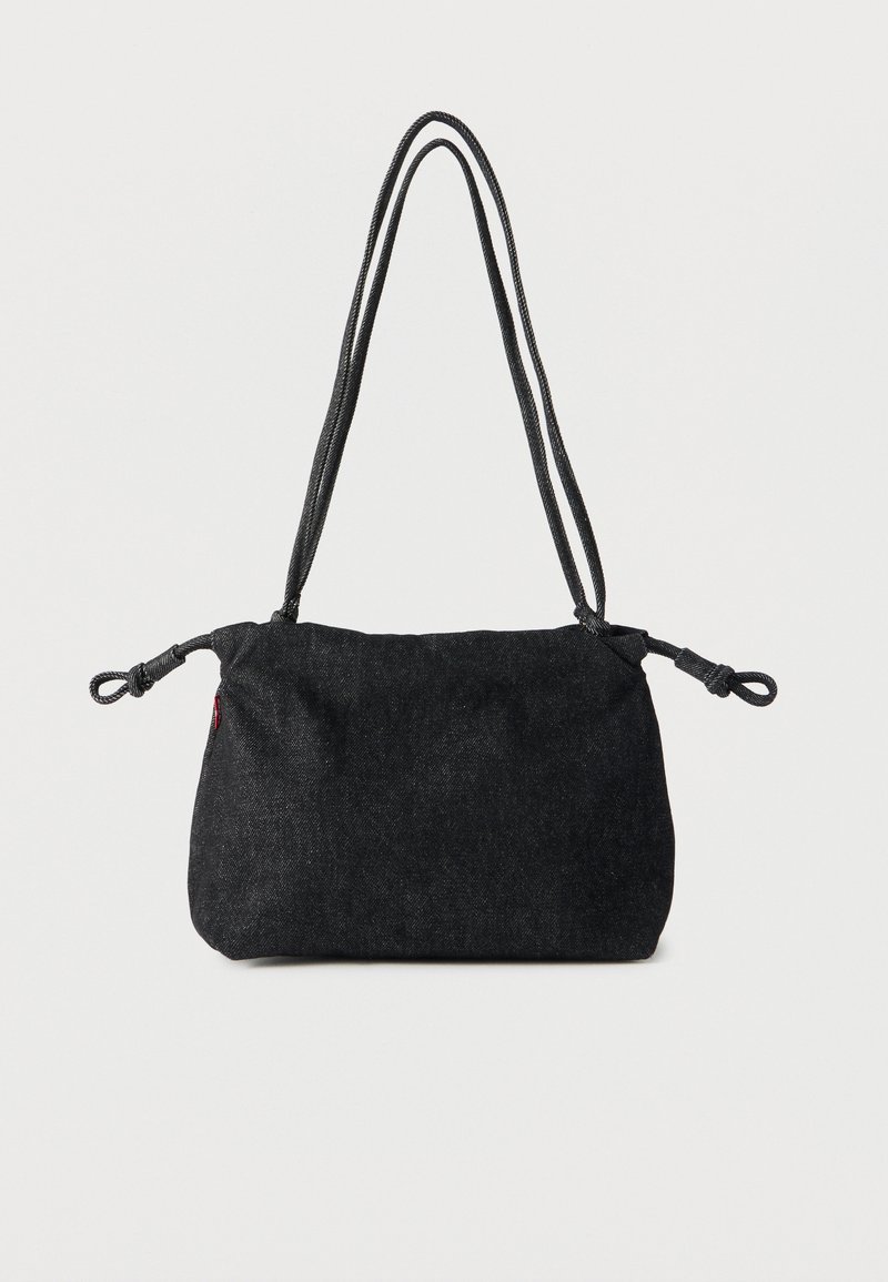 Μαύρη τσάντα ώμου από denim με διπλές ιμάντες σχοινιού και κόμπους στις άκρες από κάθε πλευρά, σε απλό λευκό φόντο.