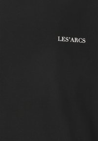 Sort bomulds t-shirt med rund halsudskæring; har hvid tekst "LES'ARCS" trykt foran. Blød tekstur med en glat overflade.