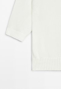 White knitted sweater sleeve and lower hem with ribbed cuffs on a plain white background.