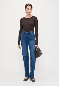 Črna dolga majica z dolgimi rokavi, modri visoko pasovi jeans, črna torbica in čevlji na peto. Jeans so ravnih nogavic z gladkim tekstilom denima.