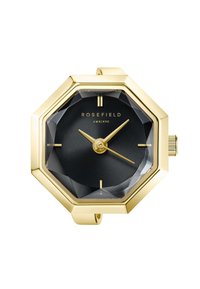 Reloj octagonal dorado con un dial negro estampado, manecillas doradas y marcadores de hora elevados. Presenta una esfera de vidrio texturizado y corona lateral.