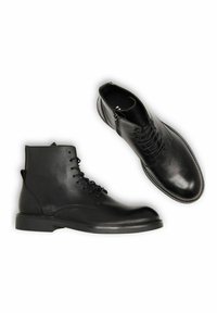Bottines noires en cuir avec une finition lisse, présentant des lacets et une fermeture à glissière sur le côté. Bout rond et design minimaliste.