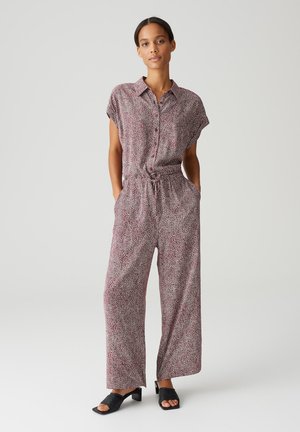 Jumpsuit stampato in tessuto leggero, maniche corte, chiusura frontale con bottoni, vita elastica, silhouette a gamba larga, caratterizzato da motivi astratti in rosso e nero.