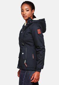 Navy blue insulated jacket with a hood, fleece lining, and multiple zipper pockets. Features a logo patch on the left sleeve and ribbed cuffs.