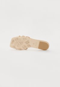 Beige heeled sandal with a textured, floral-patterned sole. Strappy design with a lightweight finish. ALDO branding on the side.