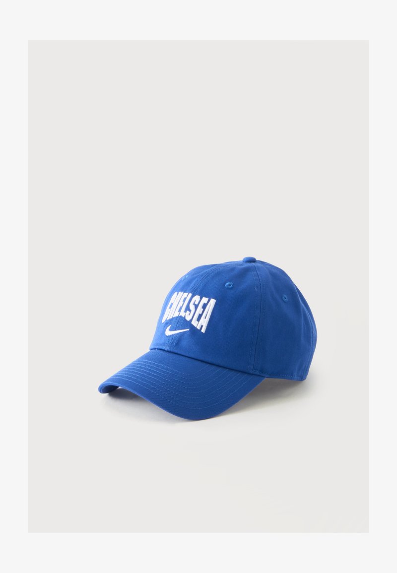 Синя бейзболна шапка с бял текст "CHELSEA" и логото на Nike swoosh отпред, показани на светъл, еднообразен фон.