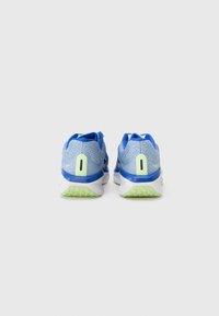 Zapatillas de running azules con parte superior de malla texturizada, acentos en verde claro y suela blanca. Presentan un logotipo minimalista y un cuello acolchado para mayor comodidad.
