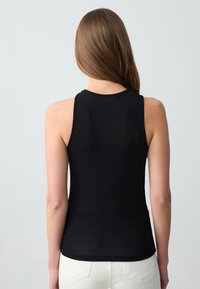 Zwarte geribde tanktop met een aansluitend ontwerp en ronde halslijn. Voorzien van dunne schouderbandjes en een gladde textuur.
