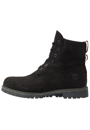 Botte noire à lacets montant à la cheville avec semelle robuste, col en tissu et logo Timberland sur le côté du talon.