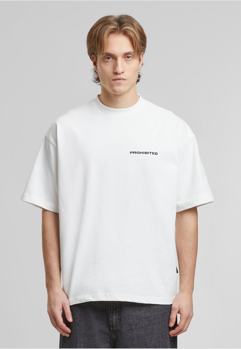 Weißes, übergroßes Baumwoll-T-Shirt mit kurzen Ärmeln, das auf der linken Seite der Brust den Text "VERBOTEN" in Schwarz aufgedruckt hat. Lässiges Design.