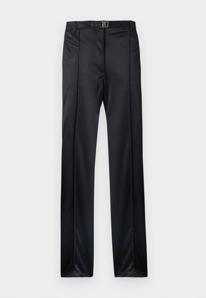 Pantalones negros a medida con un acabado liso, pliegue frontal, trabillas para cinturón y un cinturón negro fino con hebilla plateada en la cintura.