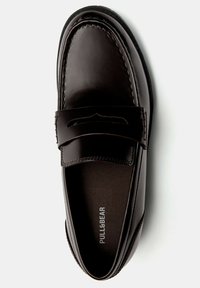 Mocassino in pelle marrone con finitura liscia, punta curva e dettagli cuciti. Presenta un motivo decorativo intagliato e un marchio testurizzato sulla soletta.