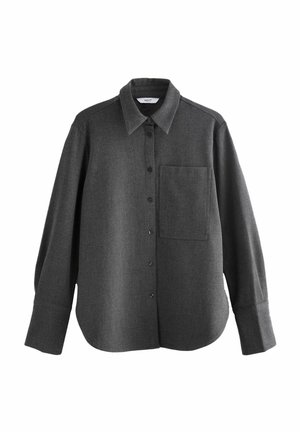 Tamsiai pilkas ilgos rankovės marškinis iš minkštos vilnos mišinio, su mygtukais priekyje, smailiu apykakle ir krūtinės kišene. Lygus paviršius, kasdieniškas siluetas.