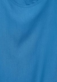 Tessuto di cotone di un colore azzurro chiaro uniforme, con una texture liscia e una leggera lucentezza, e scollatura rotonda.