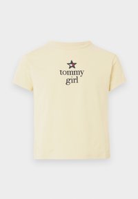 Camiseta de algodón amarilla con cuello redondo, mangas cortas, que presenta un gráfico de estrella negra sobre el texto "tommy girl" en una fuente en negrita.