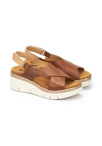 Sandalias de cuero marrón con diseño de tiras cruzadas, con correa ajustable en la parte posterior y suela de plataforma blanca elevada con acentos texturizados.