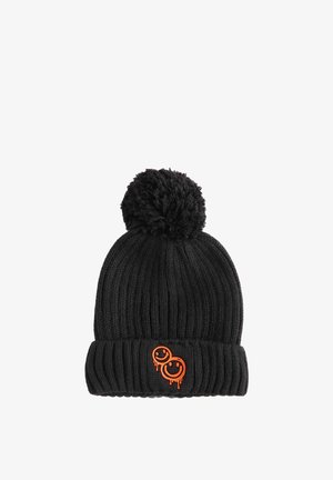 Mustat neulotut pipo, jossa on ribattua muotoilua, fluffy pom-pom päällä ja kaksi oranssia hymyilevää kasvoa roikkuvilla akcentilla.