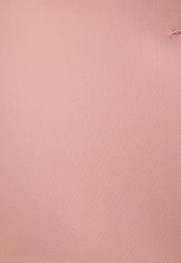 Tissu rose clair uni avec une petite déchirure effilochée en haut à droite.